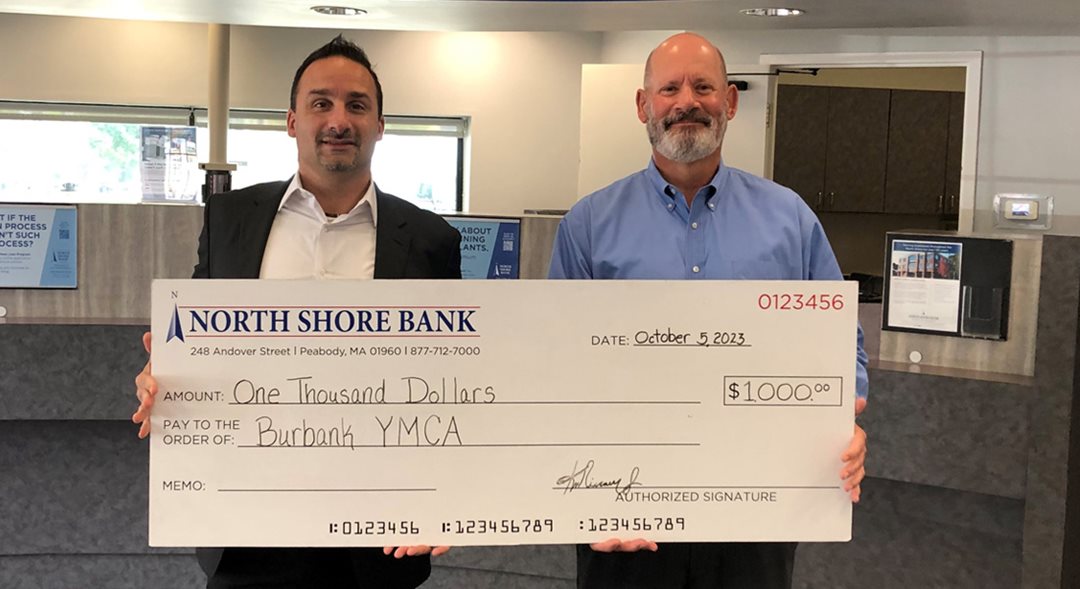 John Feudo, ED of Burbank YMCA receives $1,000 from Tom Seyffert, North Shore Bank Manager, for the Y's Halloween event.